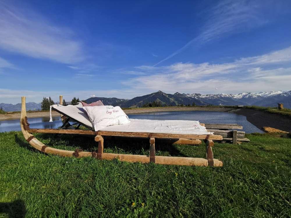 Holzliegen auf der Wiese mit Bergblick